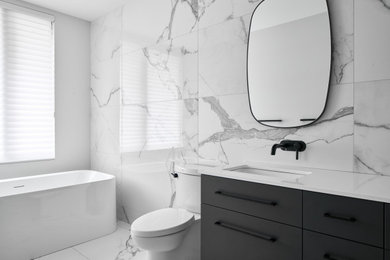 This is an example of a large contemporary master bathroom in Ottawa with flat-panel cabinets, black cabinets, a freestanding tub, a one-piece toilet, black and white tile, marble, white walls, granite benchtops, white floor, white benchtops, a shower seat, a double vanity and coffered.
