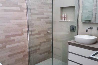 Photo of a mid-sized contemporary kids bathroom in Melbourne with flat-panel cabinets, grey cabinets, a freestanding tub, a corner shower, a one-piece toilet, gray tile, porcelain tile, grey walls, a vessel sink, engineered quartz benchtops, multi-coloured floor, a hinged shower door, grey benchtops, a niche, a freestanding vanity and decorative wall panelling.