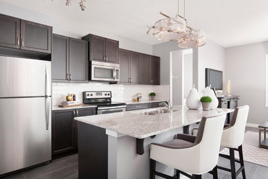 Mid-sized contemporary l-shaped open plan kitchen in Calgary with an undermount sink, recessed-panel cabinets, medium wood cabinets, granite benchtops, beige splashback, subway tile splashback, stainless steel appliances, ceramic floors and with island.