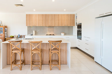 Design ideas for a large modern galley open plan kitchen in Gold Coast - Tweed with a double-bowl sink, flat-panel cabinets, light wood cabinets, quartz benchtops, grey splashback, glass sheet splashback, stainless steel appliances, ceramic floors and with island.