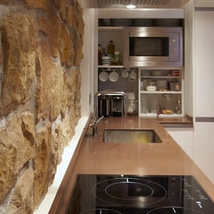 Идея дизайна: угловая кухня среднего размера в современном стиле с кладовкой, врезной раковиной, плоскими фасадами, белыми фасадами, коричневым фартуком, фартуком из известняка, техникой из нержавеющей стали, светлым паркетным полом и белым полом без острова