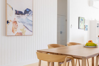 This is an example of a beach style dining room in Townsville with light hardwood floors.