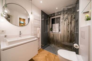 Mittelgroßes Modernes Duschbad mit flächenbündigen Schrankfronten, weißen Schränken, bodengleicher Dusche, Wandtoilette mit Spülkasten, grünen Fliesen, Keramikfliesen, weißer Wandfarbe, braunem Holzboden, Aufsatzwaschbecken, Quarzwerkstein-Waschtisch, offener Dusche und weißer Waschtischplatte in Hamburg