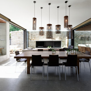 This is an example of a mid-sized contemporary dining room in Central Coast with grey walls, concrete floors, a standard fireplace, a concrete fireplace surround and grey floor.