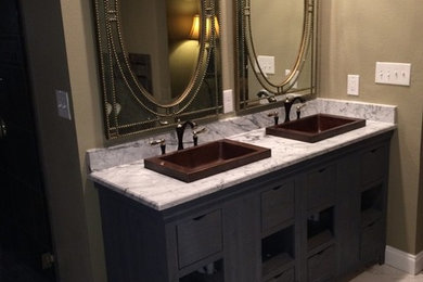 Large mountain style master marble floor and white floor freestanding bathtub photo in Dallas with brown walls, furniture-like cabinets, dark wood cabinets, a drop-in sink and marble countertops