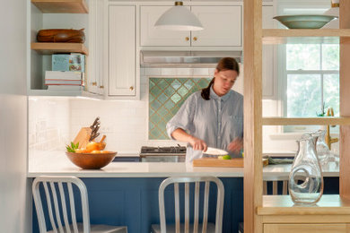Aménagement d'une cuisine américaine en U avec une crédence blanche, un électroménager en acier inoxydable et un plan de travail blanc.