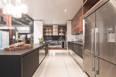 Large trendy l-shaped porcelain tile kitchen photo in Vancouver with an undermount sink, flat-panel cabinets, black cabinets, mosaic tile backsplash, stainless steel appliances and an island