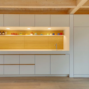 Offene, Einzeilige, Mittelgroße Nordische Küche mit flächenbündigen Schrankfronten, weißen Schränken, integriertem Waschbecken, Küchenrückwand in Braun und hellem Holzboden in München