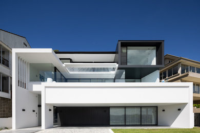 Large contemporary three-storey concrete white house exterior in Sydney with a flat roof and a metal roof.