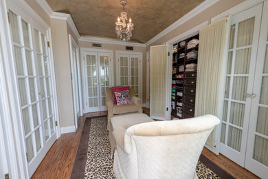 Example of a large transitional women's dark wood floor and brown floor dressing room design in New York with glass-front cabinets and white cabinets
