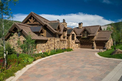 Large traditional brown two-story stone exterior home idea in Vancouver with a hip roof