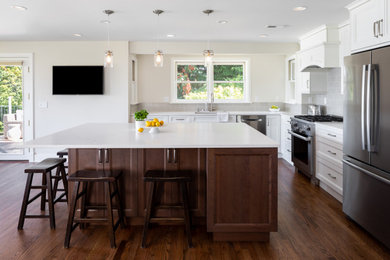 Design ideas for a large transitional l-shaped open plan kitchen in Seattle with an undermount sink, recessed-panel cabinets, white cabinets, quartz benchtops, grey splashback, ceramic splashback, stainless steel appliances, dark hardwood floors, with island, brown floor and white benchtop.
