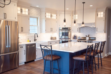 Large transitional vinyl floor and brown floor eat-in kitchen photo in Other with a farmhouse sink, beaded inset cabinets, white cabinets, quartz countertops, white backsplash, subway tile backsplash, stainless steel appliances, an island and white countertops