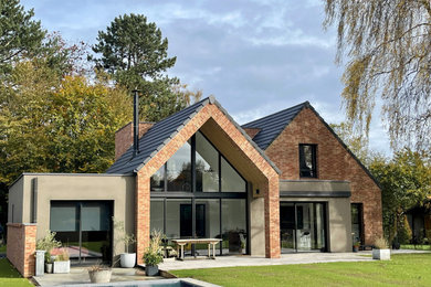 Diseño de fachada de casa negra actual extra grande de dos plantas con revestimiento de ladrillo, tejado a dos aguas y tejado de teja de barro