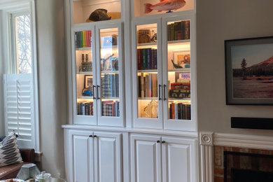 Diseño de biblioteca en casa abierta clásica de tamaño medio sin televisor con paredes beige, suelo de madera en tonos medios, todas las chimeneas, marco de chimenea de ladrillo y suelo marrón