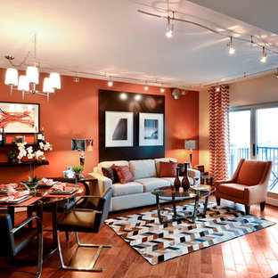 Esempio di un piccolo soggiorno minimal aperto con pareti arancioni, pavimento in legno massello medio e TV a parete