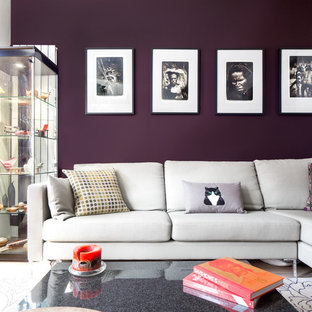 Bild på ett litet funkis allrum med öppen planlösning, med ljust trägolv, en bred öppen spis, en spiselkrans i gips, en väggmonterad TV, brunt golv och lila väggar