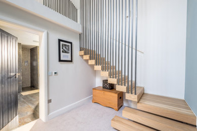 Foto de escalera suspendida minimalista de tamaño medio con contrahuellas de madera y barandilla de metal