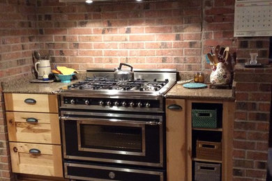 Inspiration for a mid-sized rustic u-shaped medium tone wood floor enclosed kitchen remodel in Houston with no island, recessed-panel cabinets, light wood cabinets, quartzite countertops, ceramic backsplash, black appliances and a farmhouse sink