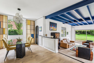 Inspiration pour un bureau minimaliste de taille moyenne avec un mur blanc, parquet clair, une cheminée d'angle et poutres apparentes.