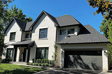 Inspiration for a large cottage white two-story brick exterior home remodel in Toronto with a mixed material roof and a black roof