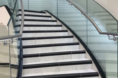Design ideas for an expansive modern tiled curved glass railing staircase in Other with tiled risers, all types of wall treatment and feature lighting.