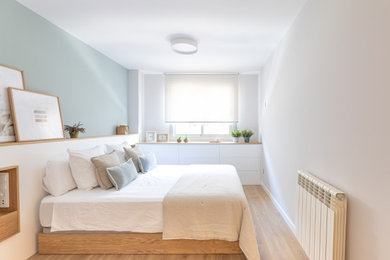 Diseño de dormitorio principal y gris y blanco escandinavo de tamaño medio con paredes grises, suelo de madera en tonos medios y suelo marrón