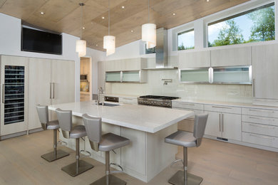 Inspiration for a large contemporary single-wall light wood floor and beige floor enclosed kitchen remodel in Denver with an undermount sink, flat-panel cabinets, light wood cabinets, beige backsplash, ceramic backsplash, paneled appliances, an island and white countertops