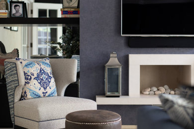 Modernes Wohnzimmer mit blauer Wandfarbe, Porzellan-Bodenfliesen, Kaminumrandung aus Stein, TV-Wand und Tapetenwänden in Surrey