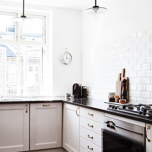 Свежая идея для дизайна: угловая кухня в скандинавском стиле с фасадами с утопленной филенкой, белыми фасадами, белым фартуком, техникой из нержавеющей стали, темным паркетным полом и фартуком из керамической плитки - отличное фото интерьера