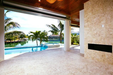 Large beach style backyard tile and rectangular infinity hot tub photo in Miami