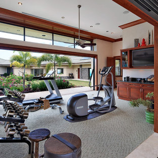 ハワイの巨大なトロピカルスタイルのおしゃれな多目的ジム (ベージュの壁、カーペット敷き、グレーの床) の写真