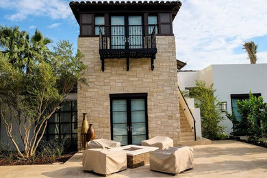 Inspiration for a mid-sized transitional beige two-story stone house exterior remodel in Los Angeles with a hip roof and a tile roof