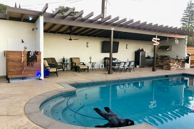 Diseño de casa de la piscina y piscina natural tradicional renovada grande a medida en patio trasero con losas de hormigón