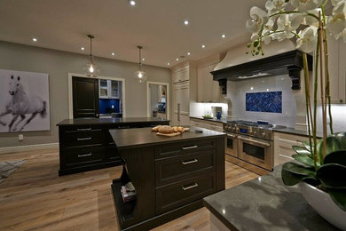 Example of a large classic l-shaped light wood floor eat-in kitchen design in Other with a drop-in sink, shaker cabinets, white cabinets, granite countertops, white backsplash, mosaic tile backsplash, stainless steel appliances and two islands