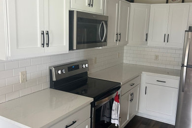 Example of a mid-sized minimalist l-shaped enclosed kitchen design in Other with an undermount sink, white cabinets, quartz countertops and white countertops