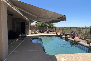 Ejemplo de piscina elevada extra grande rectangular en patio trasero con paisajismo de piscina