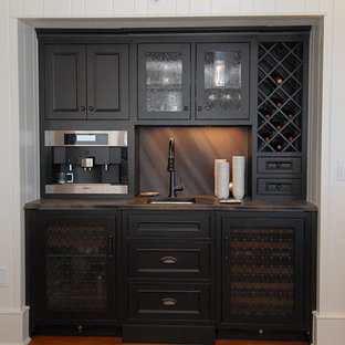オーランドの小さいビーチスタイルのおしゃれなホームバー (アンダーカウンターシンク、インセット扉のキャビネット、黒いキャビネット、御影石カウンター、茶色いキッチンパネル、石スラブのキッチンパネル、無垢フローリング) の写真