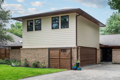 Example of a transitional beige two-story mixed siding house exterior design in Dallas with a hip roof, a shingle roof and a brown roof