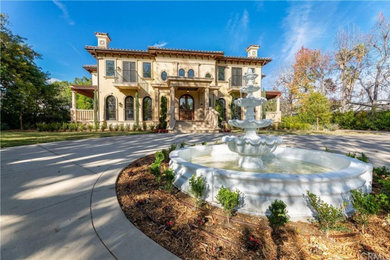 Huge tuscan beige two-story stucco house exterior photo in Los Angeles with a hip roof, a tile roof and a red roof