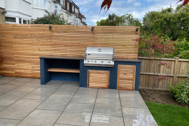 This is an example of a medium sized contemporary back full sun garden for spring in London with a wood fence.
