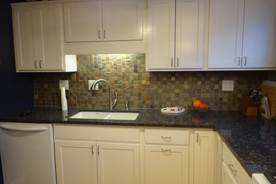Inspiration for a coastal l-shaped light wood floor enclosed kitchen remodel in Chicago with an undermount sink, shaker cabinets, white cabinets, granite countertops, multicolored backsplash, stone tile backsplash, white appliances and no island