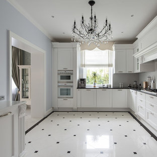 Пример оригинального дизайна: отдельная, угловая кухня в классическом стиле с фасадами с утопленной филенкой, белыми фасадами, белым фартуком и белой техникой без острова