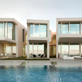 Imagen de fachada blanca, minimalista, de dos plantas, con revestimiento de vidrio