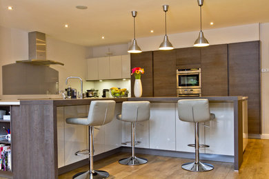 Design ideas for a contemporary open plan kitchen in Cheshire with a double-bowl sink and light hardwood floors.