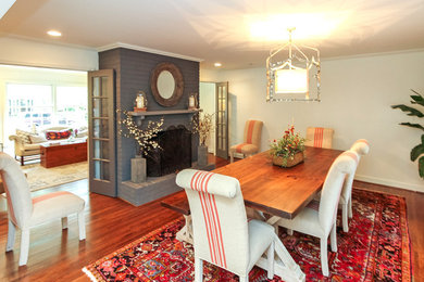 Example of a mid-sized classic dark wood floor kitchen/dining room combo design in Charlotte with white walls, a standard fireplace and a brick fireplace