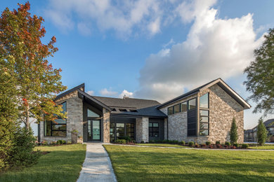 Example of a trendy gray two-story stone exterior home design in Omaha with a shingle roof and a black roof