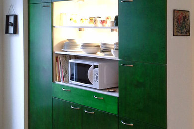 Inspiration for a small eclectic l-shaped light wood floor eat-in kitchen remodel in Montreal with a farmhouse sink, flat-panel cabinets, green cabinets, solid surface countertops, white backsplash, porcelain backsplash, white appliances and an island
