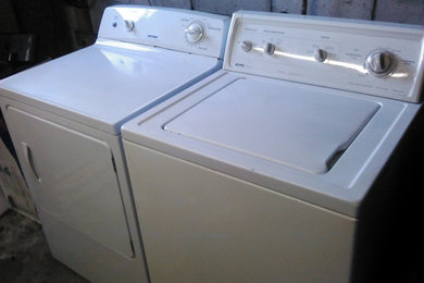 Diseño de cuarto de lavado lineal clásico renovado grande con suelo de cemento, lavadora y secadora juntas y suelo gris