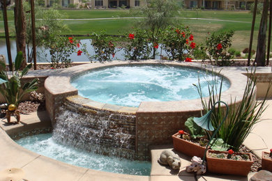 Hot tub - small tropical round natural hot tub idea in Los Angeles with decking